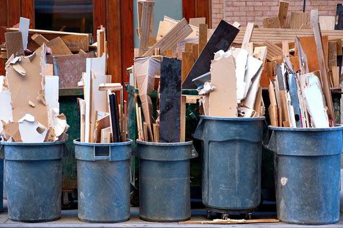 Row of garbage bins with construction debris on sidewalk